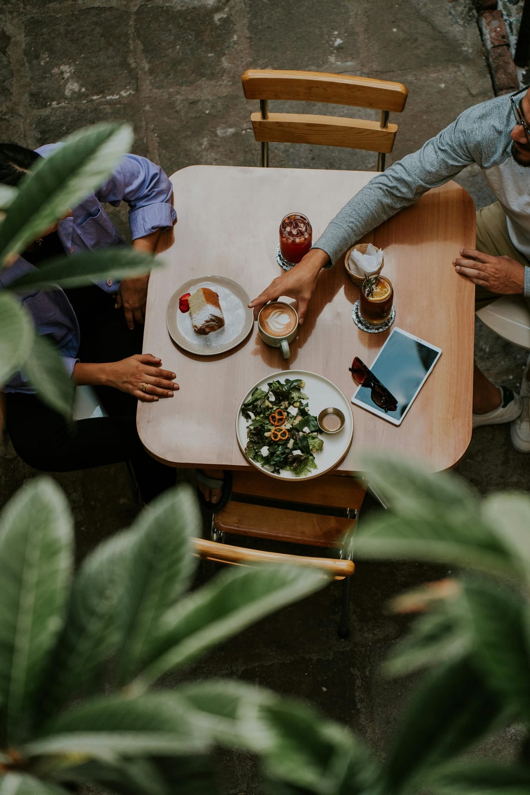 Een lange tafel vol mensen, eten en bloemen