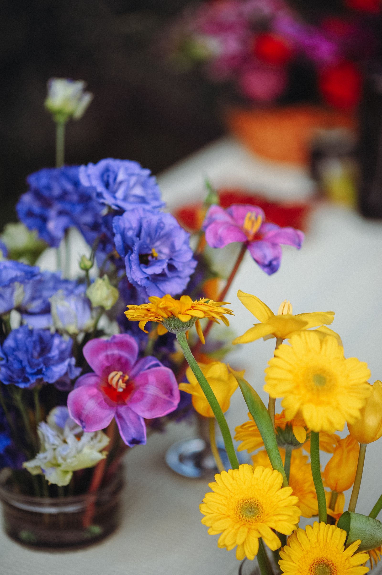 Blue, yellow and pink flowers in small vases on a table