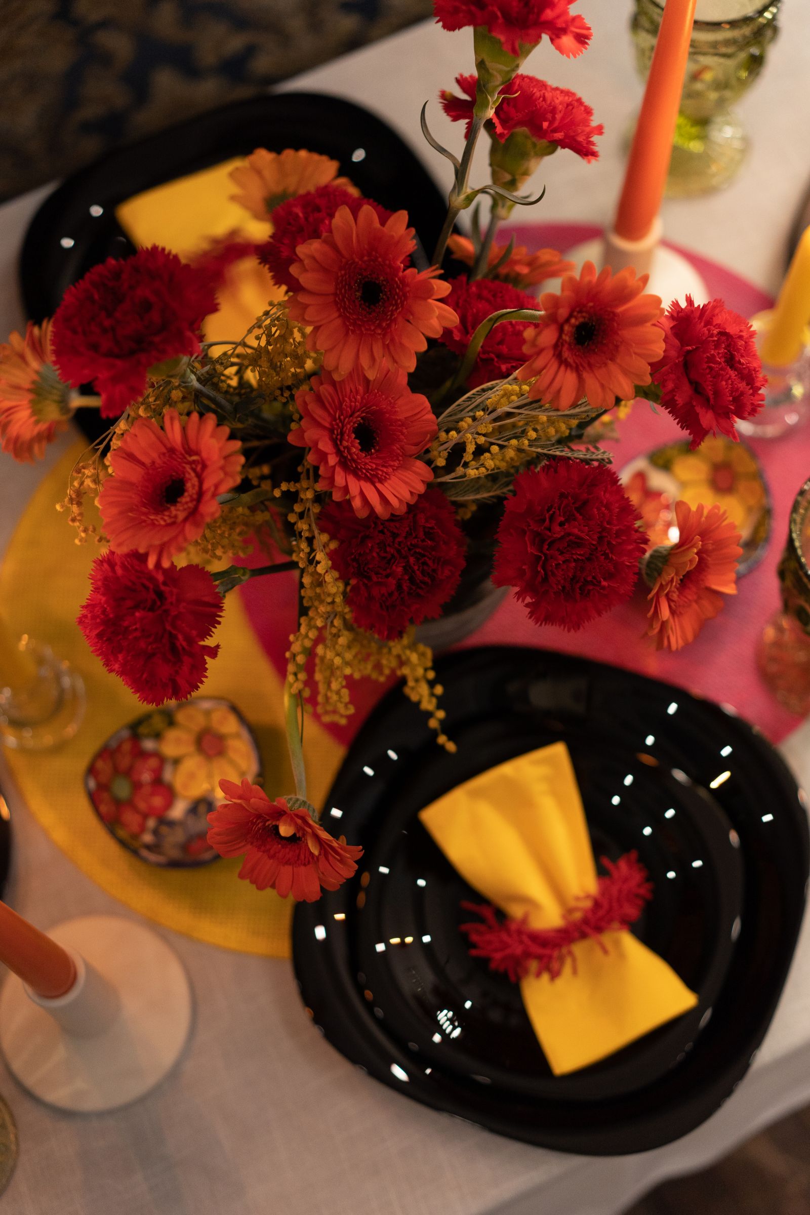 Rode en oranje gerbera’s op een tafel met gele servetten