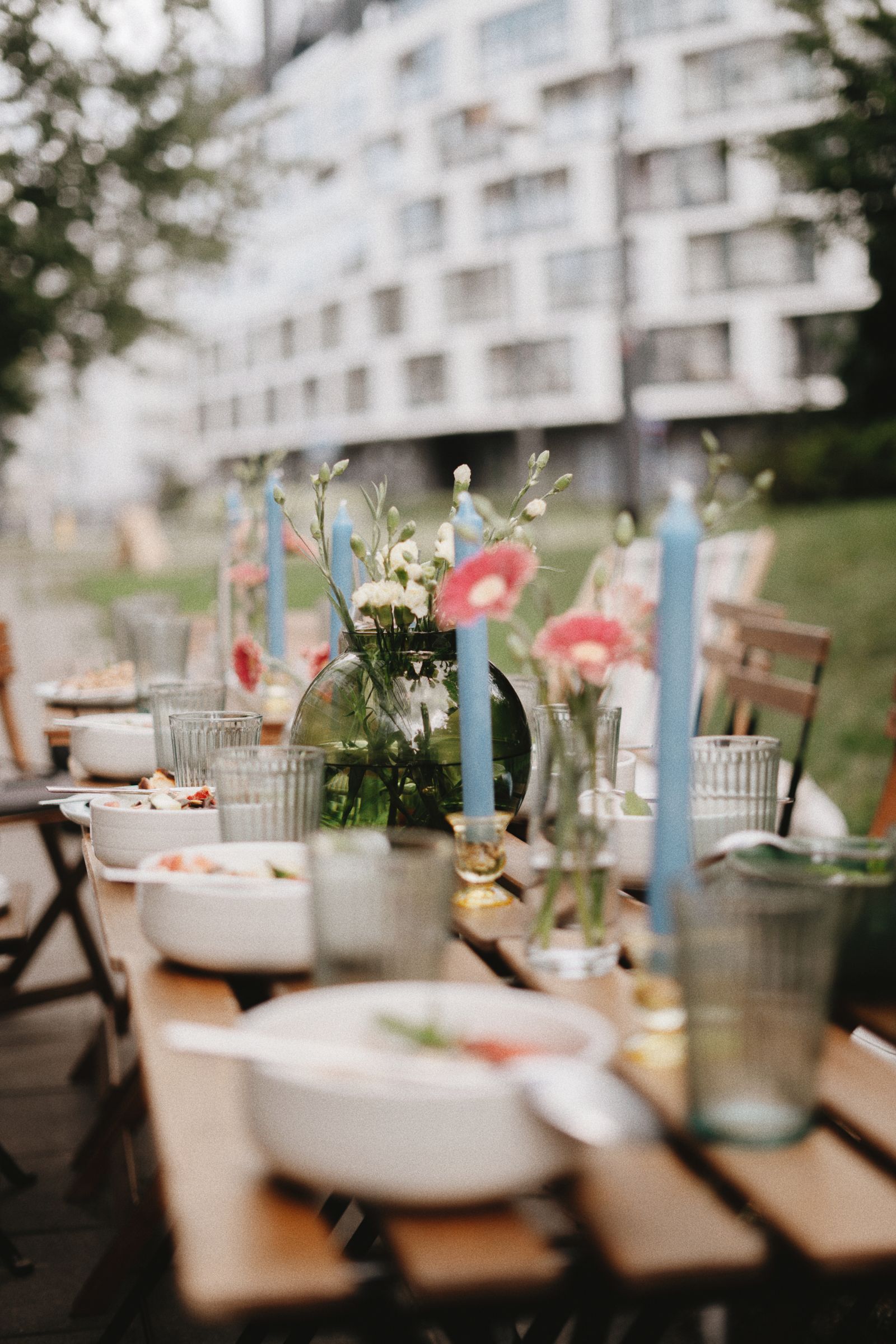 Lange gedekte tafel buiten met blauwe kaarsen en bloemen